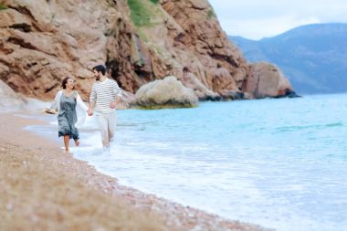 mutlu çift ıslak giysileri içinde deniz kıyısında çalışan el ele tutuşarak aşk