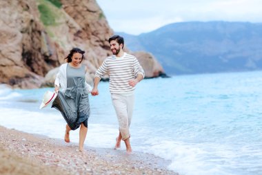 onun güzel kız arkadaşı ile elele ve deniz kıyısında çalışan mutlu yakışıklı adam 