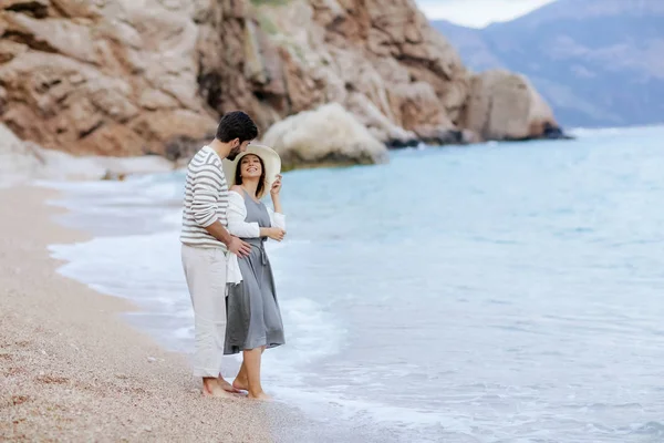 海の岸に立っているを抱き締める素朴な服でスタイリッシュな若いカップルのロマンチックな瞬間 — ストック写真