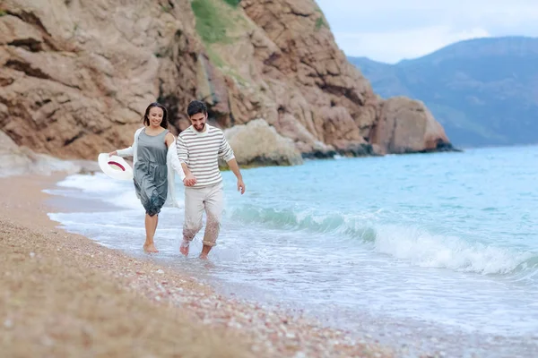 happy handsome man holding hands with his beautiful girlfriend and running on sea shore