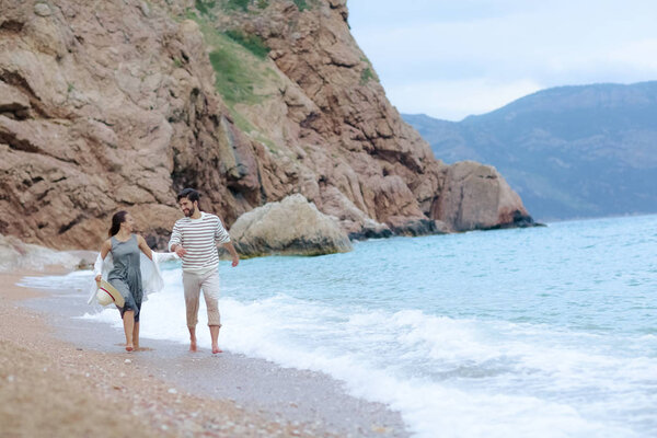 full length of happy young couple having fun running together on sea shore