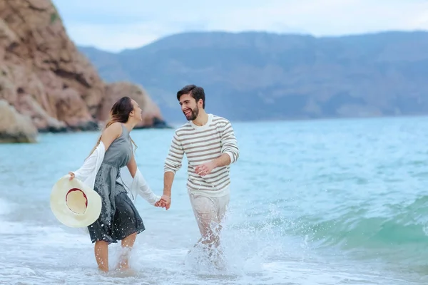 海の水に立って手を繋いで笑って幸せな若いカップル — ストック写真