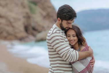 güzel kadını sarılma ve onu deniz ve dağ zemin üzerine ekose konumu olan kapsayan yakışıklı adam portresi