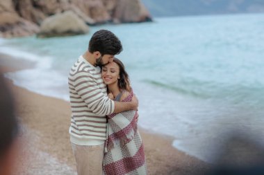 güzel kadını sarılma ve onu deniz ve dağ zemin üzerine ekose konumu olan kapsayan yakışıklı adam portresi