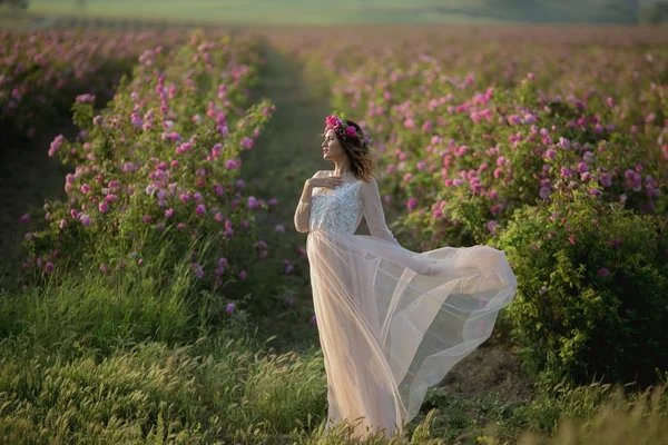 緑の自然の背景に長いドレスと花の花輪立っている女性 — ストック写真