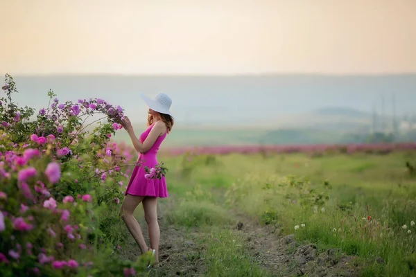 麦わら帽子とポーズと紫色の花のドレスの若い女性の完全な長さ — ストック写真