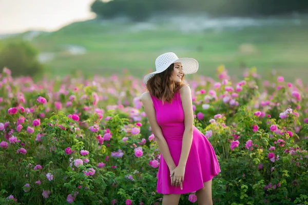 穿着紫色礼服的年轻女子和白色帽子有乐趣摆着花 — 图库照片