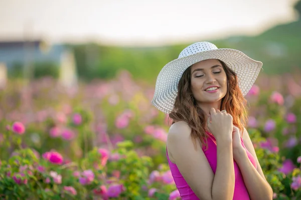 白色帽子的年轻女子摆在紫色的花朵背景 — 图库照片