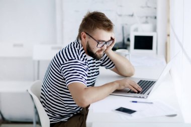 yüz ifadesi ile dizüstü bilgisayar masa başında oturan genç adam 