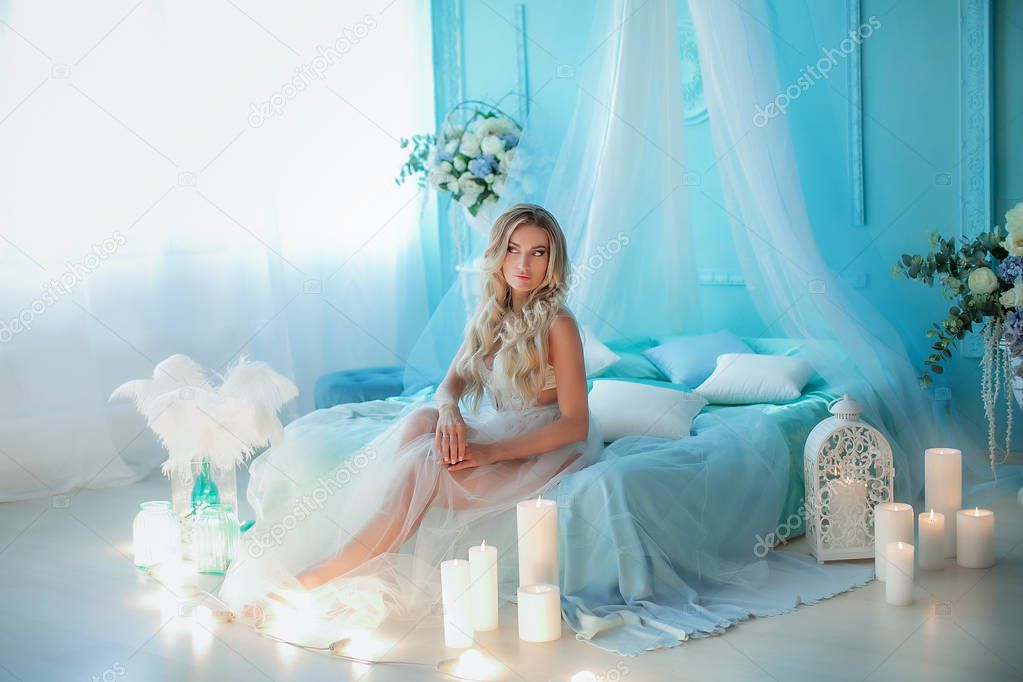 attractive blonde woman posing sitting on blue bed with decorations