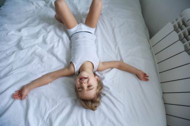 küçük çocuğa eğleniyor görüntülemek yukarıdan beyaz yatakta yatarken 