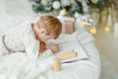 Yukarıdaki beyaz kanepe Noel ağacının altında yatan ve dilek listesi yapma ufaklık görüntülemek