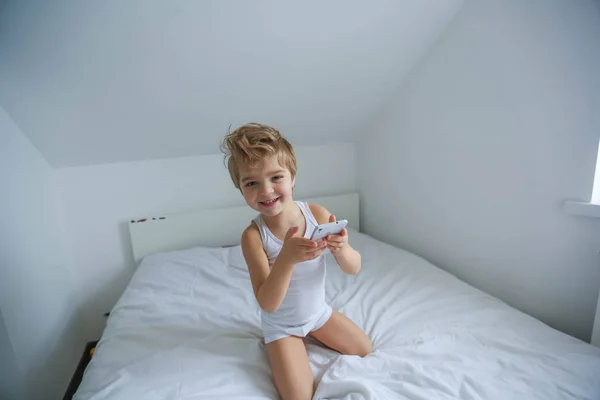 View Little Boy Sitting White Bed Playing Smartphone — Stock Photo, Image