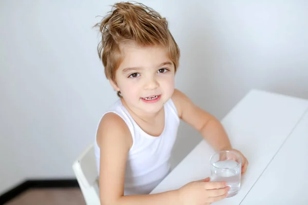 Legrační Malý Chlapec Sedí Stolu Bílá Sklenicí Vody — Stock fotografie