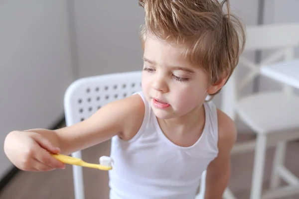 Retrato Niño Divertido Sosteniendo Cepillo Dientes Amarillos Sentado Silla Blanca — Foto de Stock