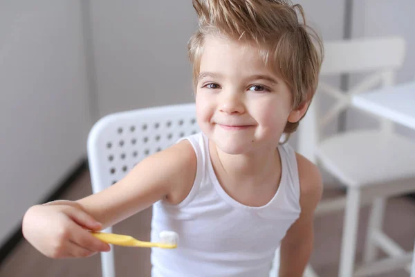 Retrato Niño Divertido Sosteniendo Cepillo Dientes Sonriendo Sentado Silla Blanca — Foto de Stock