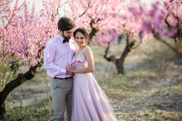 Vackra Bruden Och Brudgummen Poserar Trädgården Mot Blommande Träd — Stockfoto