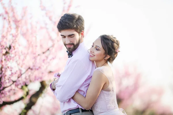 Vackra Bruden Och Brudgummen Poserar Trädgården Mot Blommande Träd — Stockfoto