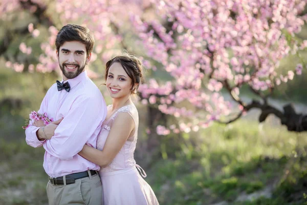 Vackra Bruden Och Brudgummen Poserar Trädgården Mot Blommande Träd — Stockfoto