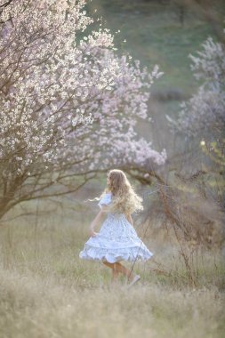 genç güzel sarışın kız mavi elbiseyle çiçek açması bahçede poz 
