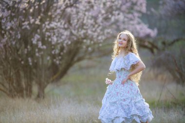 genç güzel sarışın kız mavi elbiseyle çiçek açması bahçede poz 