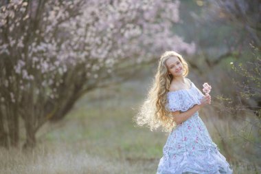 genç güzel sarışın kız mavi elbiseyle çiçek açması bahçede poz 