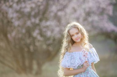 genç güzel sarışın kız mavi elbiseyle çiçek açması bahçede poz 