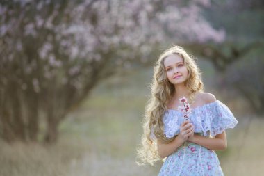 genç güzel sarışın kız mavi elbiseyle çiçek açması bahçede poz 