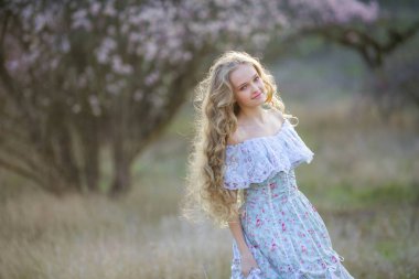 genç güzel sarışın kız mavi elbiseyle çiçek açması bahçede poz 