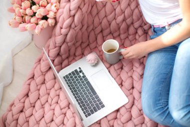 Sıcak bir sabah, kabarık bir ekose, kahve, bir dizüstü bilgisayar ve güzel kadın ayakları