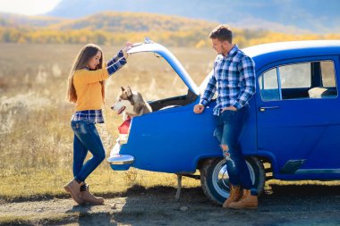 Erkek ve kadın mavi araba husky köpek ile poz 