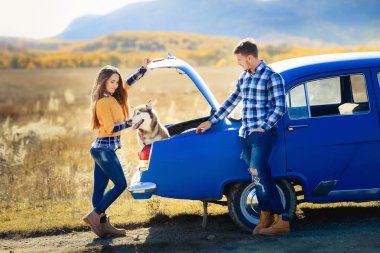 Erkek ve kadın mavi araba husky köpek ile poz 