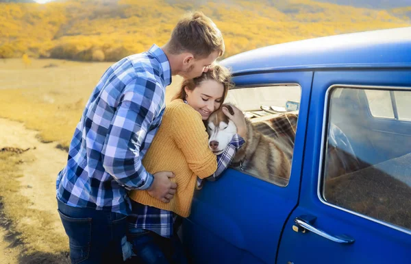 愛とハスキー犬の青い車に近いポーズのカップル — ストック写真