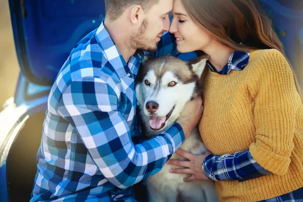 男性と女性が青い車でハスキー犬と一緒にポーズ — ストック写真