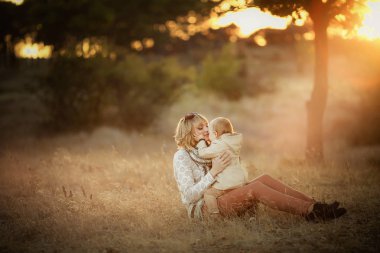 Anne ve kızı günbatımında sonbahar bahçede poz 