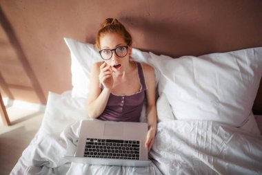 yatakta yatan ise dizüstü kullanan kadın 