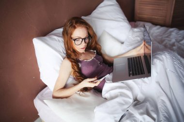 yatakta yatan ise dizüstü kullanan kadın 