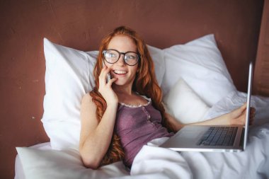 yatakta yatan ise dizüstü kullanan kadın 