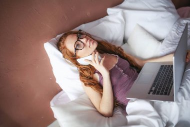 yatakta yatan ise dizüstü kullanan kadın 