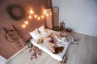 Kırmızı saçlı kadın rahat yatak üzerinde Noel içinde poz oda dekore edilmiştir. 