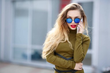 Açık havada yeşil elbise ve güneş gözlüğü takmış poz genç güzel kadın 