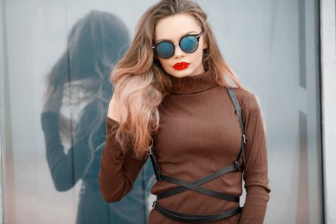 Açık havada kahverengi elbise ve güneş gözlüğü takmış poz genç güzel kadın 