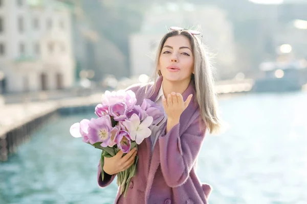 beautiful woman with tulips posing near water