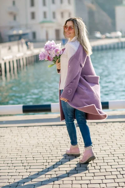 beautiful woman with tulips posing near water