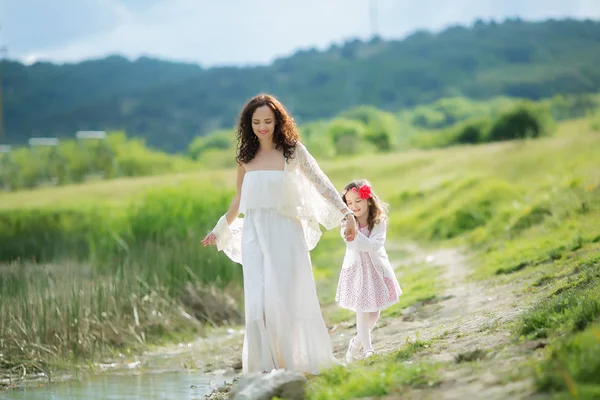 beautiful mother and daughter posing outdoors near lake