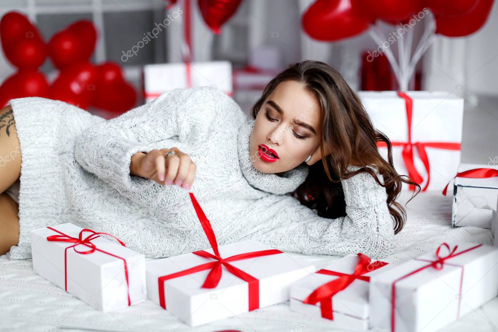 beautiful brunette woman posing in studio with gift boxes 
