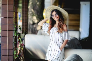 Açık çizgili elbise ve hasır şapka giyen genç güzel kız portresi 