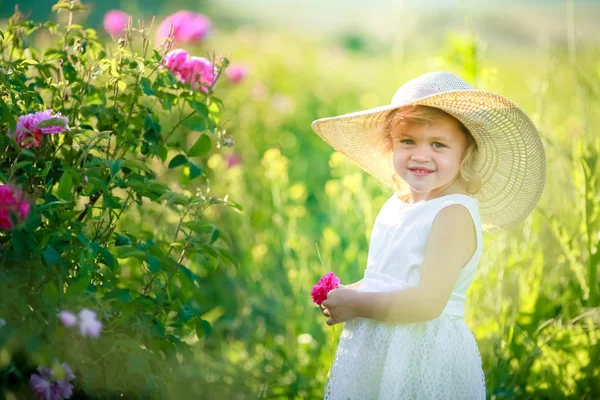 可爱的小女孩摆在绿色领域的白色礼服和帽子 — 图库照片