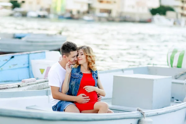 pregnant wife with husband posing outdoors on the pier