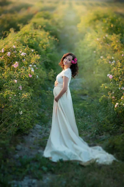 白いドレスの緑のフィールドでポーズ美しい妊婦 — ストック写真